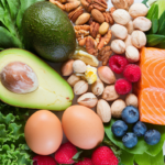 A flat-lay of a healthy, colorful spread of low-carb foods such as leafy greens, avocado, eggs, salmon, nuts, and berries.